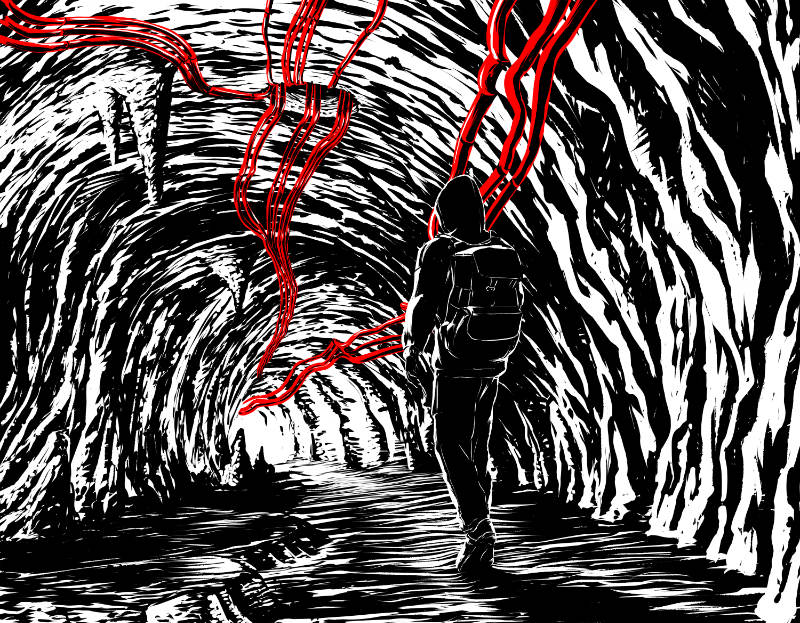 A person walking down a tunnel with wires.
